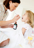 A mother giving her sick little girl some cough syrup. - Copyright – Stock Photo / Register Mark
